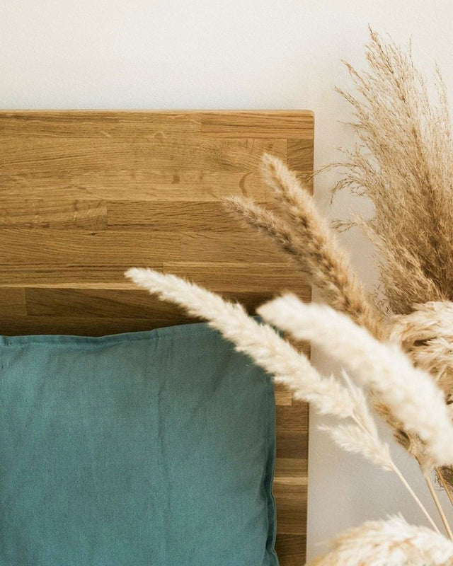 Łóżko drewniane z litego dębu w jasnym wnętrzu pościelą lnianą