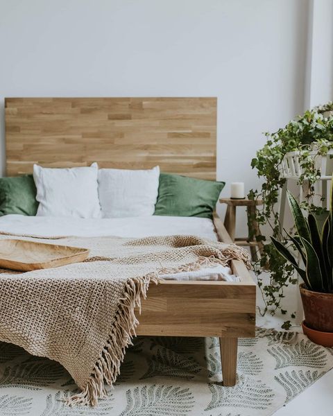 Łóżko drewniane z akcentami zieleni w poszewkach na poduszki roślinach