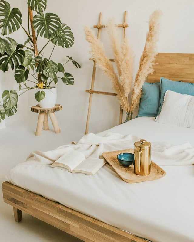 Łóżko drewniane z litego dębu w jasnym wnętrzu z kwiatami i roślinami